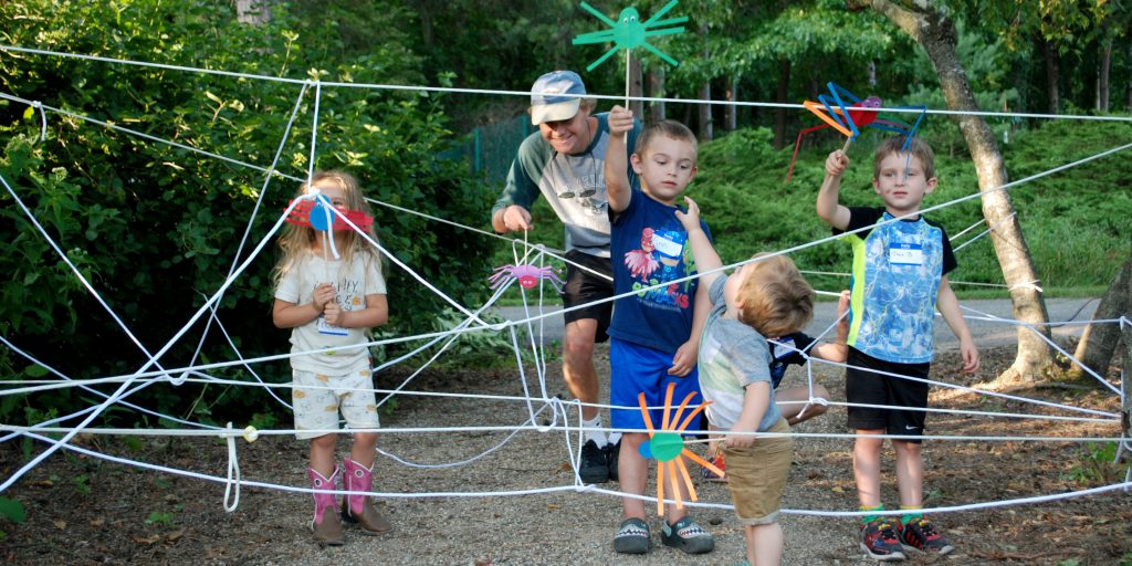 Children play with handmade spider toys at a 2019 Wild Wednesdays event.