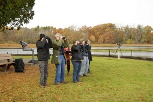 Six people using binoculars to view birds on the shore of Wintergreen Lake