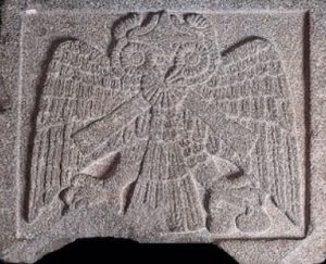 An image of an owl is carved into stone.