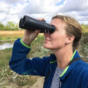 Kristy Taylor peers at the sky through binoculars.