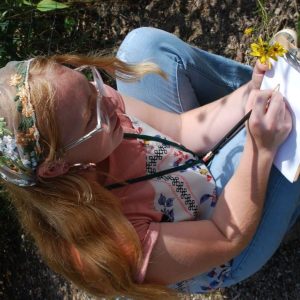 Image of girl sitting on ground sketching on a pad