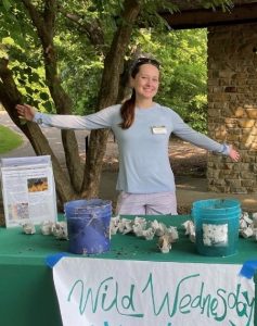 Madison Aprill standing with outstretched arms at Wild Wednesday table
