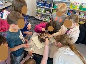 Students gathered around a soil block with mushrooms, examining it with magnifying glasses