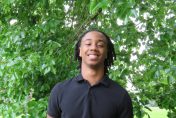 Dakarai Rogers standing in front of a green, leafy tree