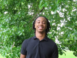 Dakarai Rogers standing in front of a green, leafy tree
